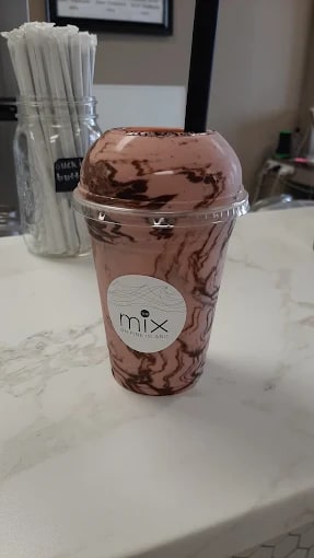 A real MIX cup: dusty-pink drink with chocolate marbling under a clear dome lid