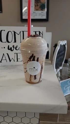 A real MIX cup: light mocha drink with chocolate drizzle, a red straw and crumbles on the dome